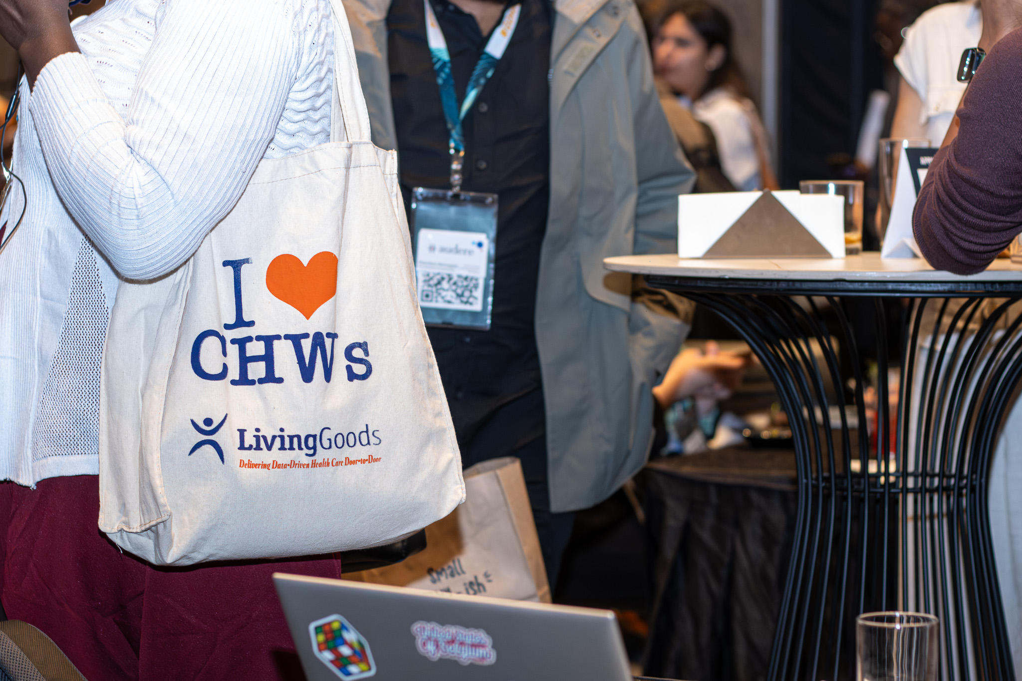 A conference attendee carrying an 'I love CHWs' Living Goods tote bag